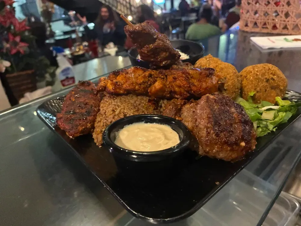 Grilled skewers, falafel, and rice served on a platter in the cafe